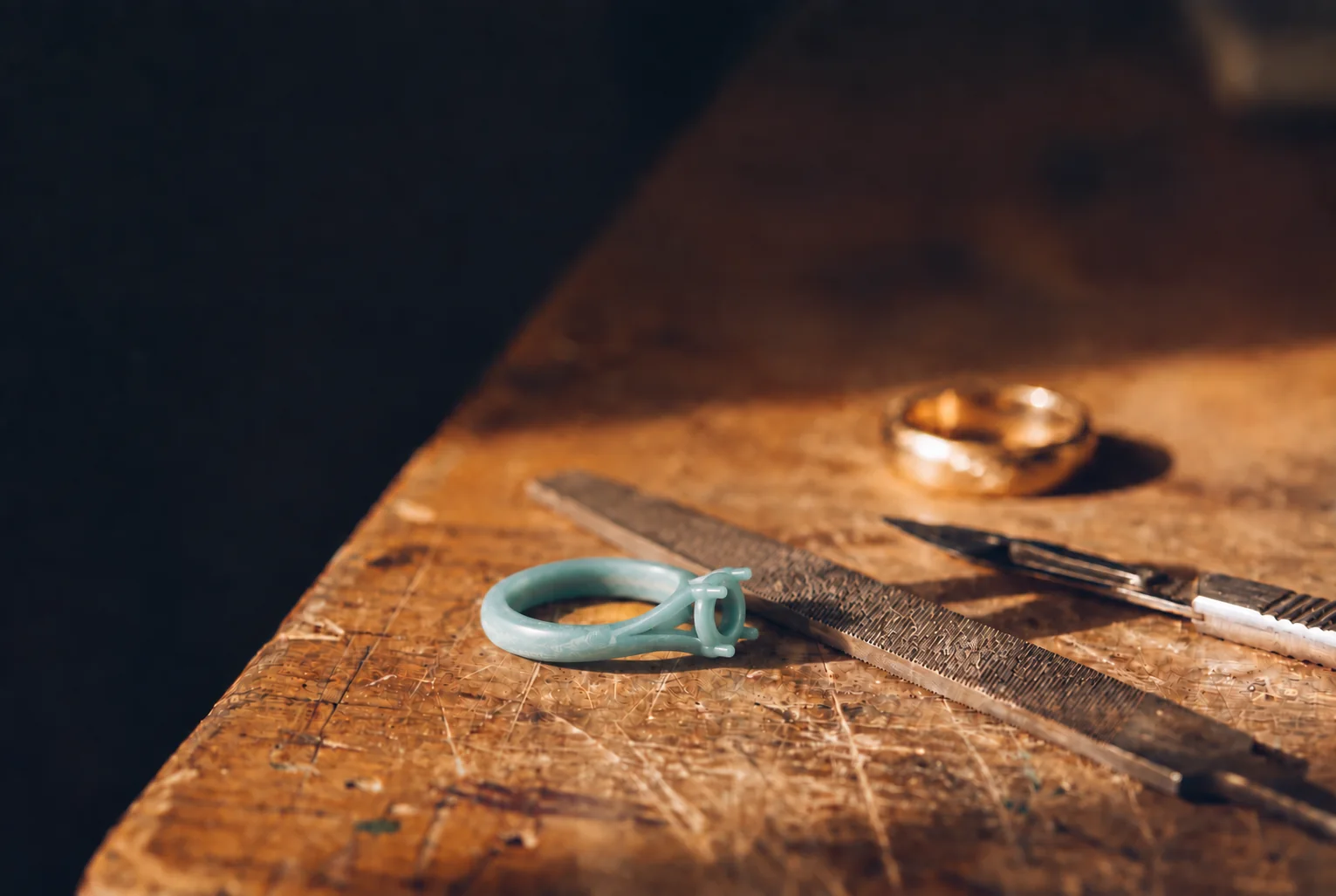 Maquette en cire d'une bague sur l'établi, lime et outils de joaillier